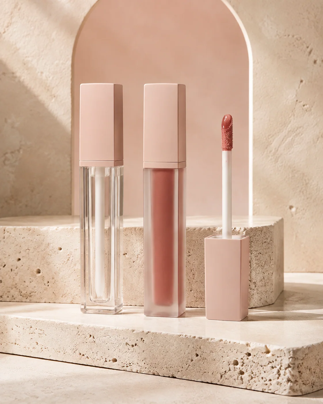 Lip gloss tubes and doe-foot applicators on warm stone