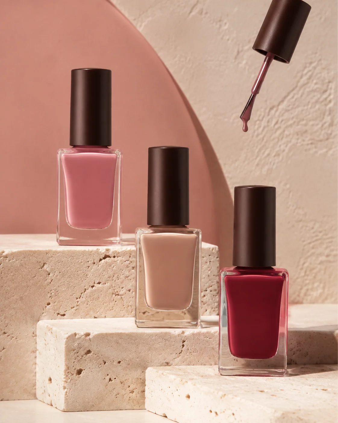 Unbranded nail polish bottles with brush components on warm stone